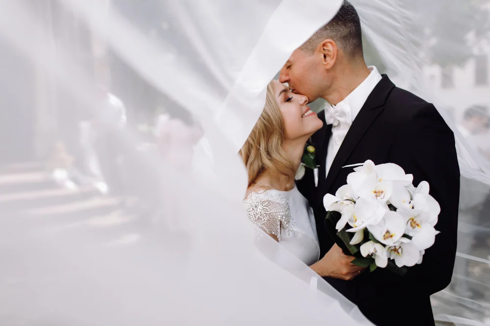 7 Tendências de Decoração de Casamento para 2023 4 groom black tuxedo hugs tender stunning bride while they stand